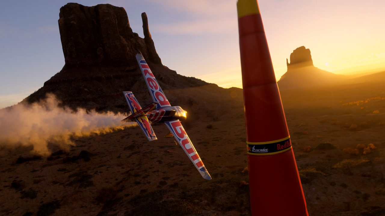 An aerobatic plane racing past desert buttes
