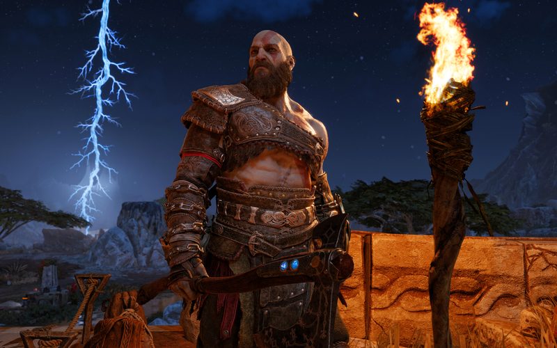 Kratos standing before a lightning-lit sky beside a burning torch